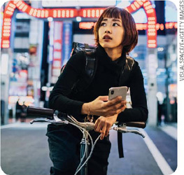 IMAGEM: uma mulher japonesa anda de bicicleta em tóquio. FIM DA IMAGEM.