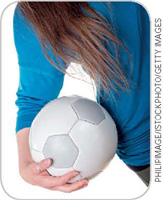 IMAGEM: uma menina segura uma bola de futebol. FIM DA IMAGEM.