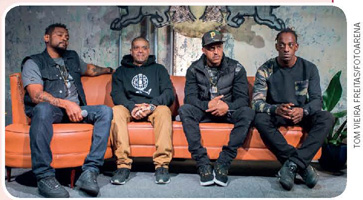 IMAGEM: os integrantes do grupo de rap racionais émícis sentados em um sofá. FIM DA IMAGEM.