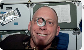 IMAGEM: o astronauta clayton anderson observa uma bola de água flutuar devido à falta de gravidade. FIM DA IMAGEM.