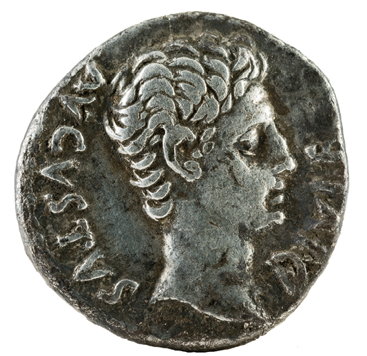 Moeda. Frente de uma moeda metálica redonda, com a imagem de um homem visto de perfil.