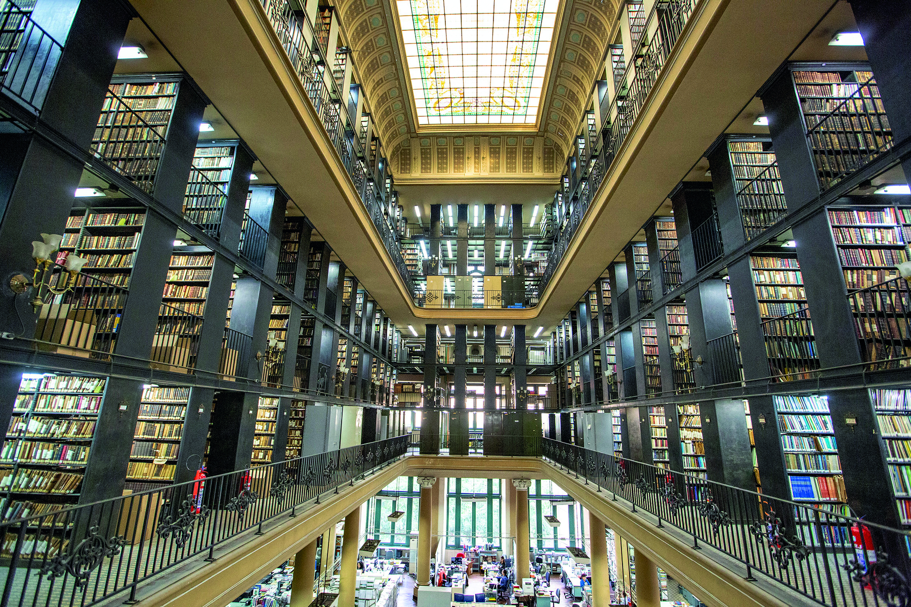 Fotografia. Interior de uma biblioteca, com 6 andares equipados com estantes repletas de livros.