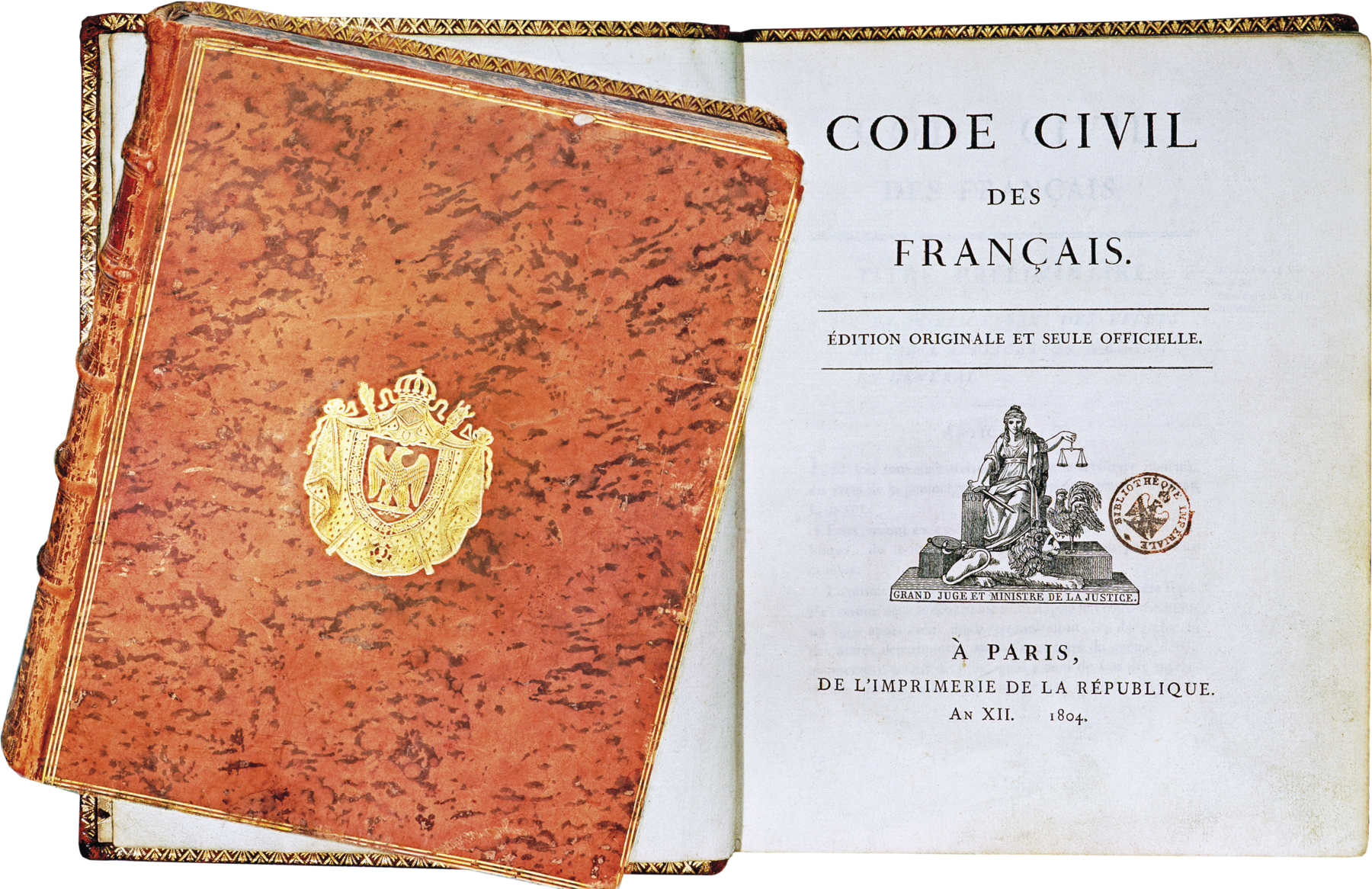 Fotografia. Destaque para um livro aberto contendo o texto, em francês, 'Código Civil francês'. À esquerda, imagem do livro fechado, com a capa marrom clara e um brasão dourado ao centro.