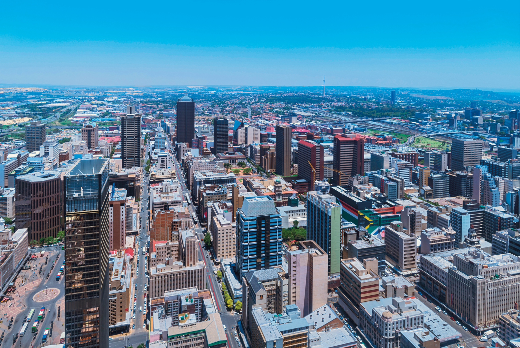 Fotografia. Vista aérea de uma cidade em zona densamente urbanizada, repleta de edifícios altos.