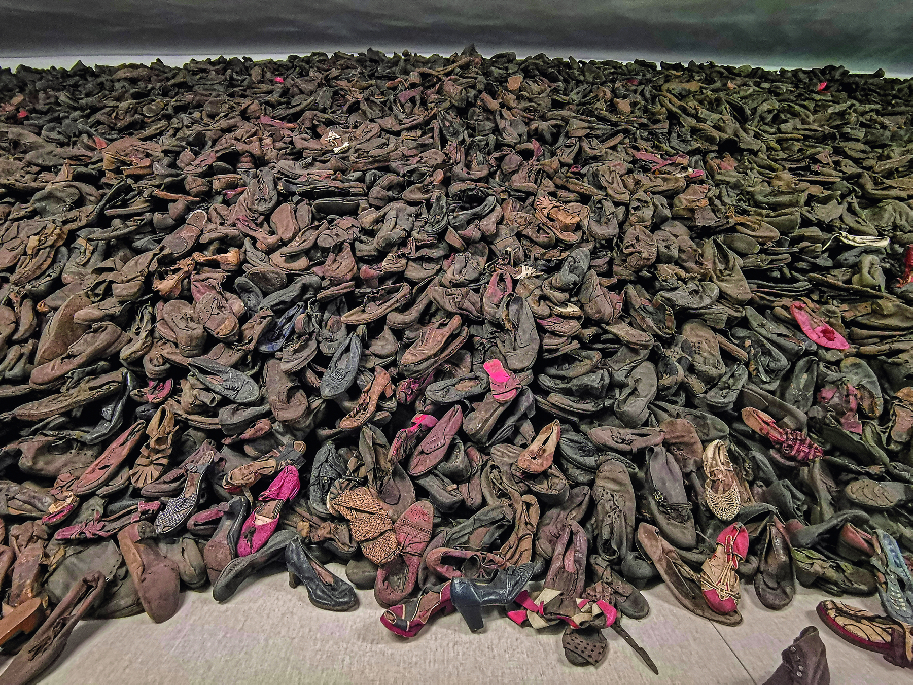 Fotografia. Uma imensa pilha de sapatos desgastados amontoados.