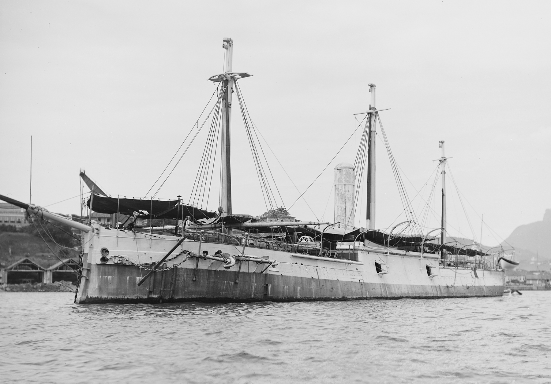 Fotografia em preto e branco. Um navio sobre águas. Possui três mastros, com diversas cordas presas ao topo.