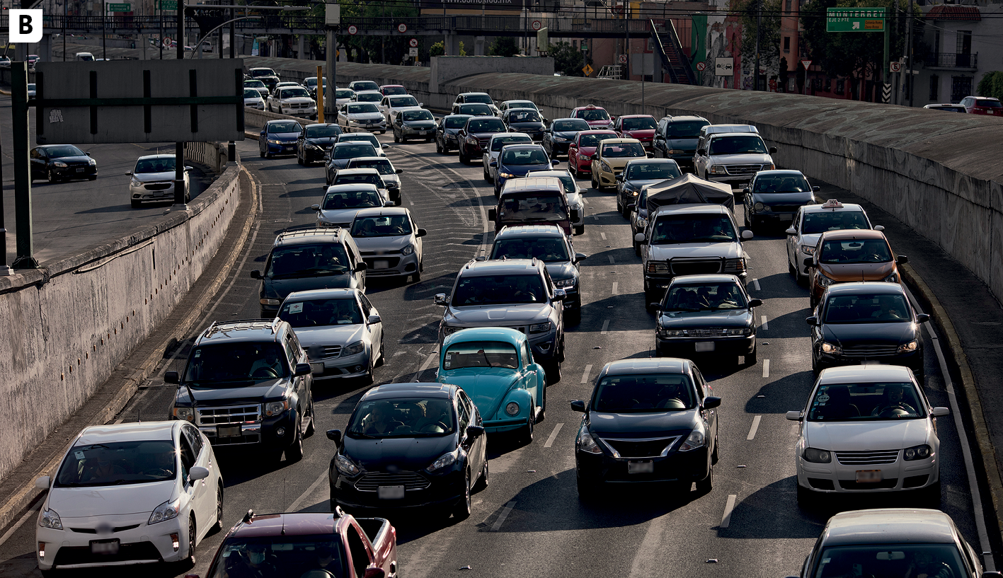 Fotografia B. Vista de uma avenida, destacando uma das pistas com quatro faixas de rolamento completamente ocupadas por automóveis. À esquerda, parte de um rua com dois carros circulando. À direita, a outra pista da avenida na direção contrária e algumas construções.