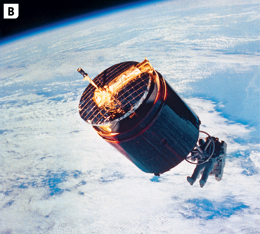 Fotografia B. Destaque para um satélite antigo de formato cilíndrico em órbita no espaço. Na parte de baixo do satélite, há um astronauta. No segundo plano, vista do Planeta Terra azul com muitas nuvens.