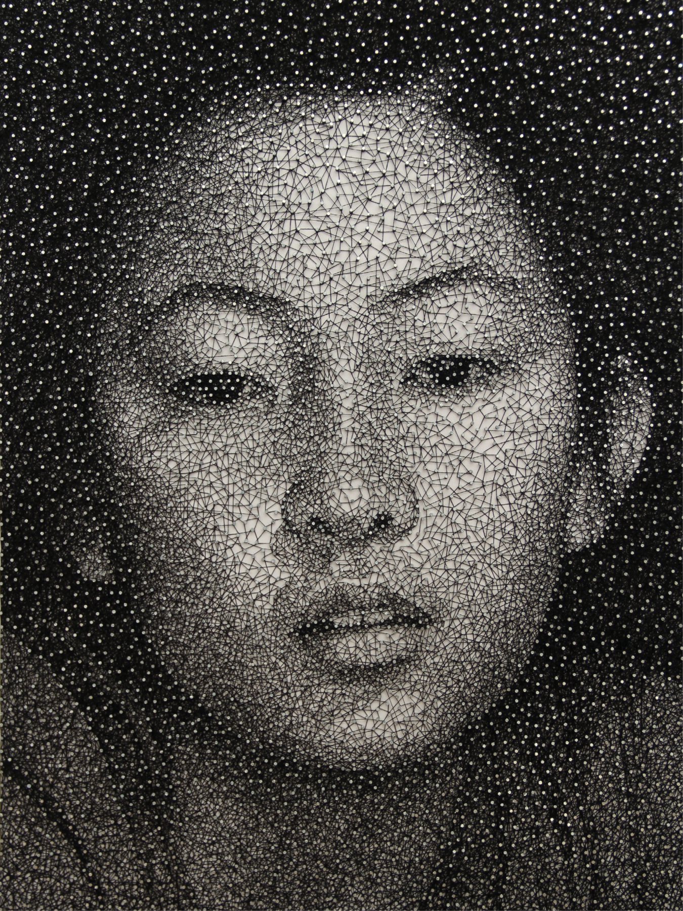 Fotografia.
Painel com pregos e linhas esticadas entre eles formando um rosto de mulher oriental, olhos pequenos, sobrancelha arqueada e boca pequena.