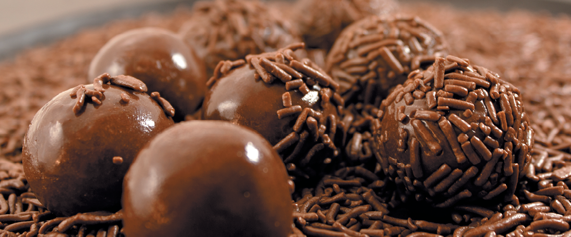Fotografia. Brigadeiros sobre granulado de chocolate.