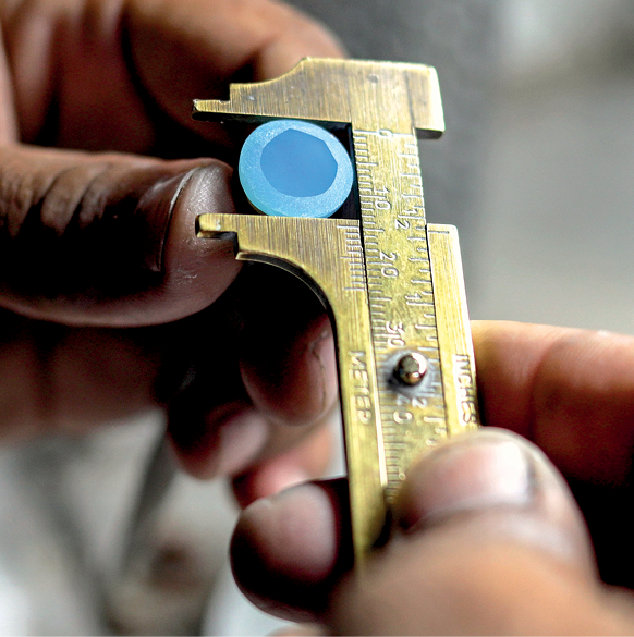 Fotografia.
Mão segurando um paquímetro medindo um objeto circular.