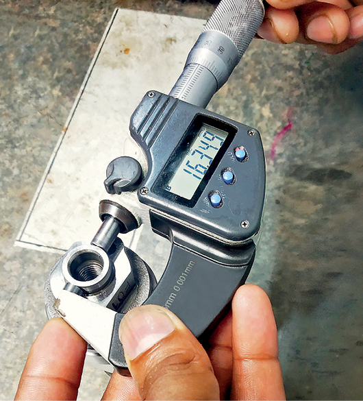 Fotografia.
Mão segurando um micrômetro medindo um objeto.