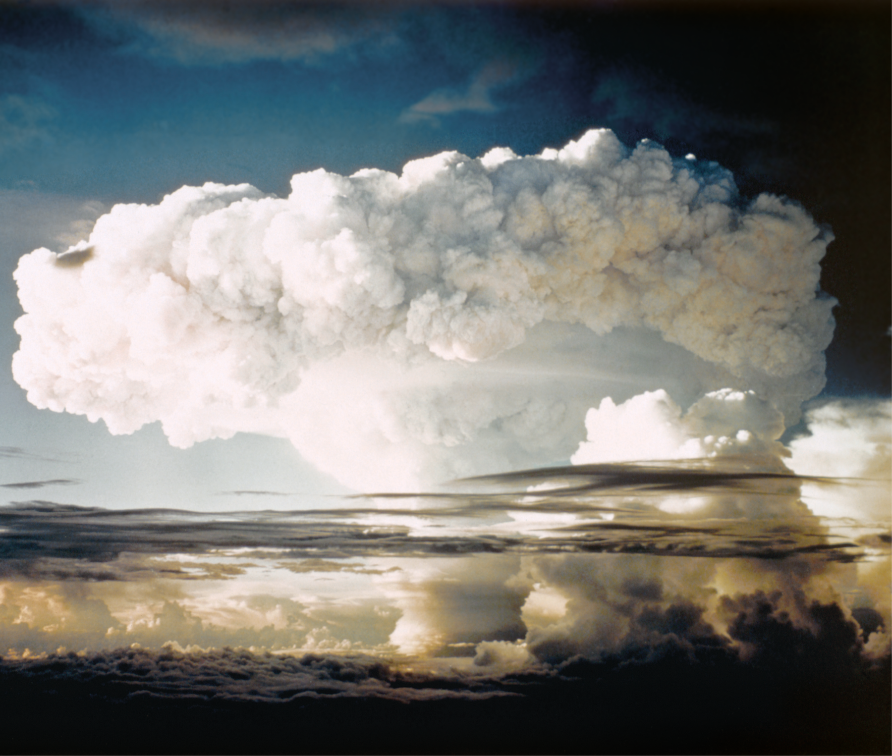 Fotografia. Grande nuvem de explosão nuclear com bomba de hidrogênio em uma ilha. Ao fundo, céu azul.