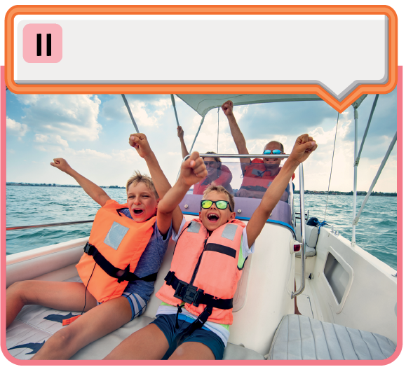 Fotografia. À frente, duas pessoas usando coletes salva-vidas sentadas em um barco com as mãos para cima e sorrindo. Atrás delas há mais duas pessoas sentadas com coletes salva-vidas e as mãos para cima.