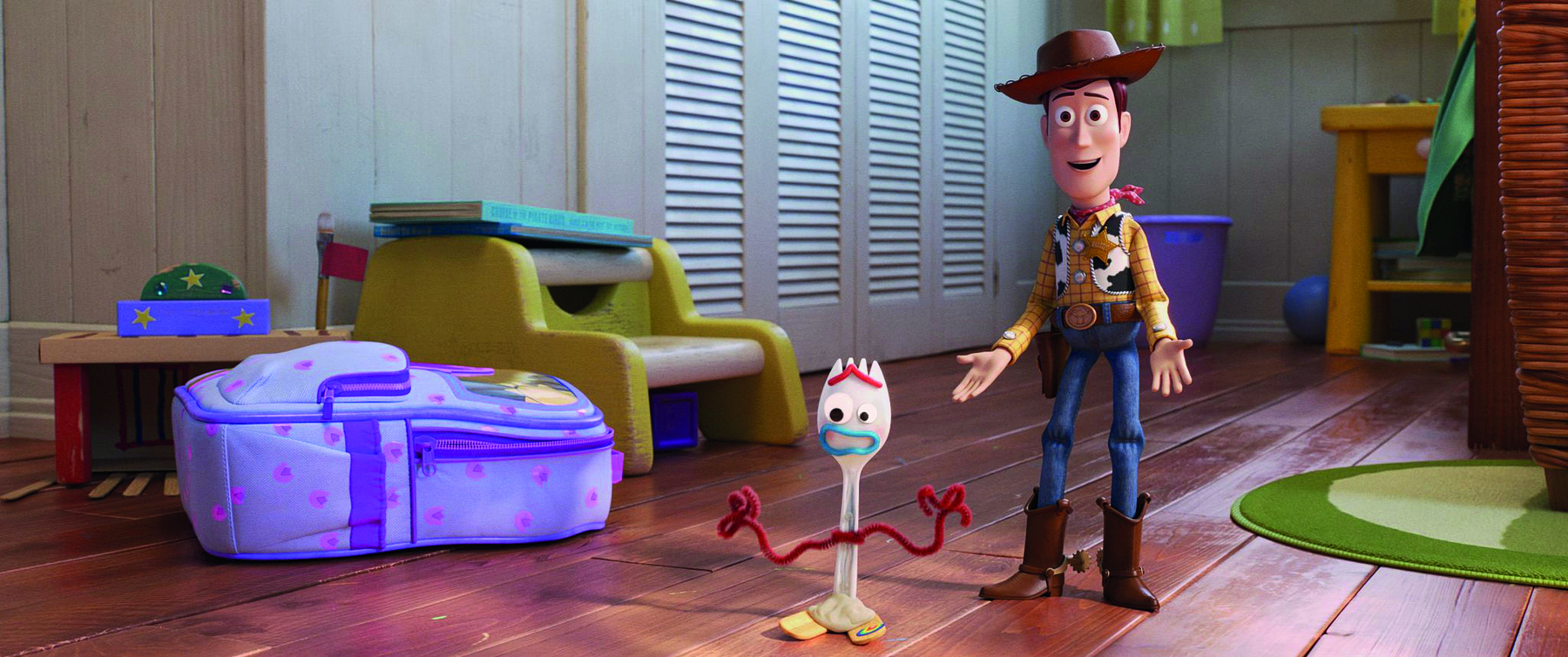 Captura de tela. Cena de filme de animação. Woody, um boneco usando chapéu redondo e marrom, camiseta xadrez, colete malhado, calça jeans e botas, com um distintivo no peito, está com os braços abertos. À frente dele está Forky, um garfo de plástico com braços e um rosto feito com materiais recicláveis. Ao fundo, há uma mochila no chão e alguns brinquedos.