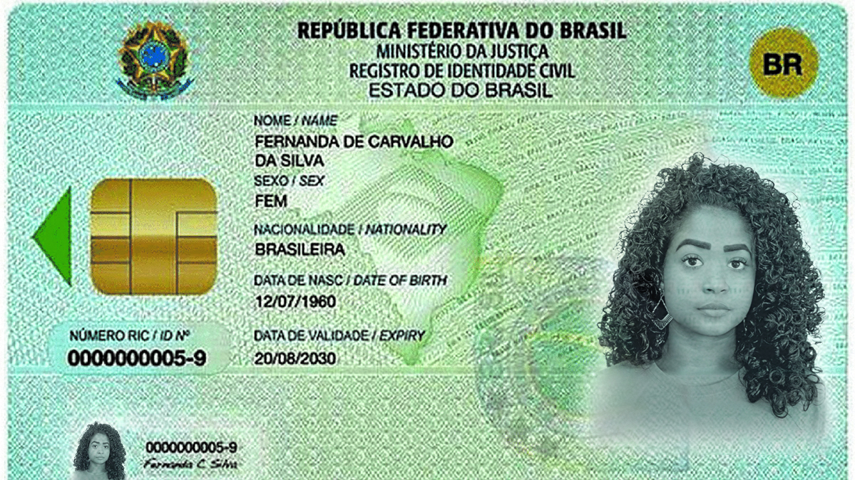 Fotografia. Documento de identidade em formato retangular, disposto na horizontal. Na parte superior esquerda, há o brasão da REPÚBLICA FEDERATIVA DO BRASIL. Na parte superior central lê-se REPÚBLICA FEDERATIVA DO BRASIL, MINISTÉRIO DA JUSTIÇA, REGISTRO DE IDENTIDADE CIVIL, ESTADO DO BRASIL. No canto superior direito há a sigla BR. Abaixo, à esquerda, há um chip dourado e, abaixo dele, o NÚMERO RIC BARRA ID NUMBER ZERO ZERO ZERO ZERO ZERO ZERO ZERO ZERO ZERO CINCO DÍGITO NOVE. No centro, há as informações: NOME BARRA NAME: FERNANDA DE CARVALHO DA SILVA. SEXO BARRA SEX: FEM. NACIONALIDADE BARRA NATIONALITY: BRASILEIRA. DATA DE NASC BARRA  DATE OF BIRTH: doze de julho de mil novecentos e sessenta. DATA DE VALIDADE BARRA EXPIRY: vinte de agosto de dois mil e trinta. À direita, há a fotografia em preto e branco de uma menina de cabelo cacheado e comprido e sobrancelhas grossas. No canto inferior esquerdo há uma miniatura da foto da menina ao lado do número de seu documento e de sua assinatura.