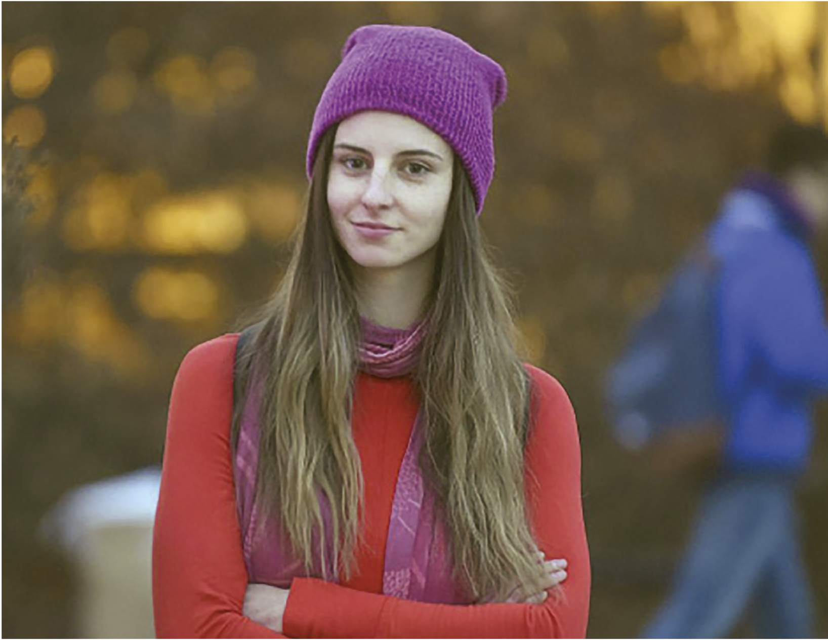 Fotografia. Mulher de cabelo castanho liso longo, casaco vermelho, suéter rosa e um gorro rosa.