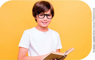 IMAGEM: um menininho de cabelos lisos e castanhos, com olhos claros e pele branca, usando óculos de grau e segurando um livro aberto. FIM DA IMAGEM.