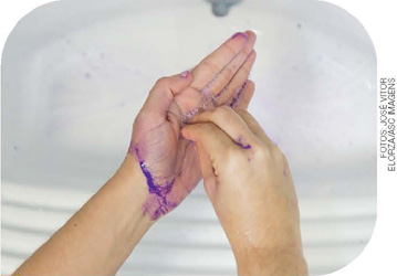 IMAGEM: uma das mãos está segurando o polegar da outra mão, vemos que a tinta já começa a sair. FIM DA IMAGEM.