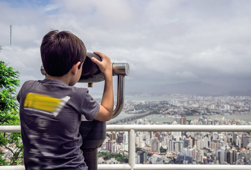 IMAGEM: na abertura do capítulo 1, um menino está de costas e usa um binóculo para observar, de um ponto alto, a paisagem de uma cidade com prédios, uma ponte sobre uma baía e montanhas ao fundo. FIM DA IMAGEM.