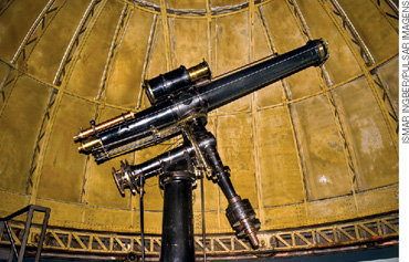 IMAGEM: grande telescópio no interior de um observatório em formato de cúpula. FIM DA IMAGEM.