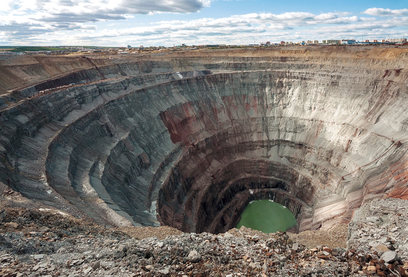 IMAGEM: página dupla. grande cratera em decorrência da mineração. o fundo do buraco está cheio de água. FIM DA IMAGEM.