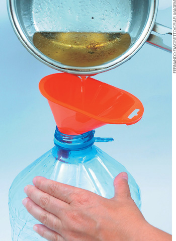 IMAGEM: samuel transferindo o óleo usado de cozinha para uma garrafa de plástico, com a ajuda de um funil. FIM DA IMAGEM.