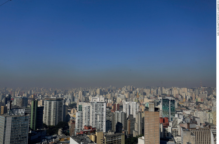 IMAGEM: faixa cinza entre o céu azul e os prédios mostrando a poluição de uma grande cidade. FIM DA IMAGEM.