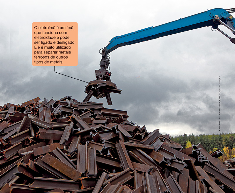 IMAGEM: enorme pilha de metais ao ar livre onde um guindaste os retira com um eletroímã materiais feitos de ferro. FIM DA IMAGEM.