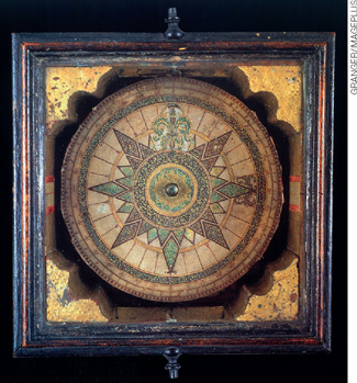 IMAGEM: uma antiga bússola de navegação feita de madeira, metal e mosaico de pedras. FIM DA IMAGEM.