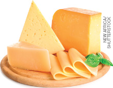 IMAGEM: tábua de madeira redonda com pedaços e fatias de queijo sobre ela. FIM DA IMAGEM.