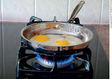 IMAGEM: dois ovos dentro de umqa frigideira em um fogão com o fogo aceso. FIM DA IMAGEM.