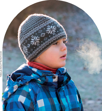 IMAGEM: menino com roupas de inverno, respira em um ambiente frio onde se observa que da sua boca sai uma fumaça branca. FIM DA IMAGEM.