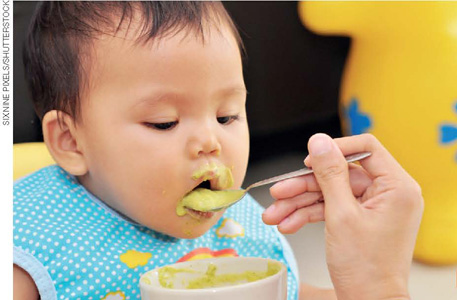 IMAGEM: pessoa alimentando bebê com papinha. FIM DA IMAGEM.