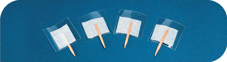 IMAGEM: quatro pedaços de plástico cortados em formato de quadrado, com metades de palitos de dente presos em um de seus lados por fita adesiva. FIM DA IMAGEM.