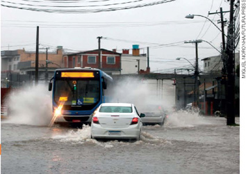 IMAGEM: um ônibus e alguns carros enfrentando uma enchente. FIM DA IMAGEM.