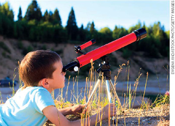 IMAGEM: um garotinho observando o céu através de uma luneta. FIM DA IMAGEM.