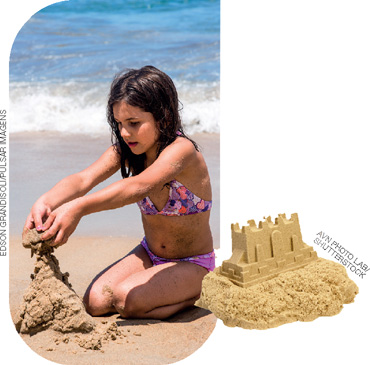 IMAGEM: uma menina branca com cabelo preto está fazendo um castelo de areia na praia. em destaque ao lado da fotografia, há uma imagem de um castelo de areia pronto. FIM DA IMAGEM.