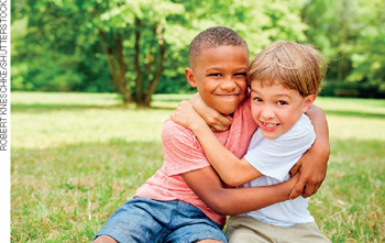 IMAGEM: duas crianças se abraçam e sorriem sentadas em um gramado. FIM DA IMAGEM.