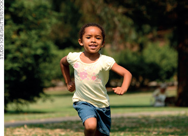 IMAGEM: uma menina negra com cabelos presos para trás está correndo em um gramado. FIM DA IMAGEM.