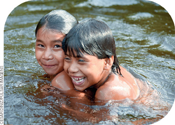 IMAGEM: duas crianças indígenas brincam dentro de um rio. elas têm cabelos pretos e lisos. FIM DA IMAGEM.