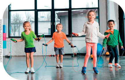 IMAGEM: crianças pulam corda em uma sala de ginástica. elas usam tênis e roupas leves. FIM DA IMAGEM.