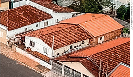 IMAGEM: fotografia aérea de uma casa e duas casas vizinhas, uma em cada lado. há também a calçada. FIM DA IMAGEM.