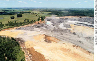IMAGEM: área de extração de carvão mineral. possui um terreno irregular e nota-se marcas de pneus no solo, provocadas pelas máquinas usadas para essa atividade. FIM DA IMAGEM.