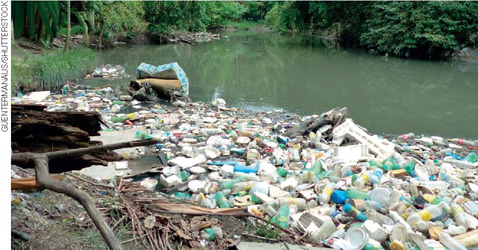 IMAGEM: muito lixo acumulado às margens de um rio. FIM DA IMAGEM.