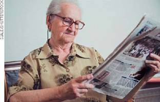 IMAGEM: uma idosa lendo jornal. FIM DA IMAGEM.