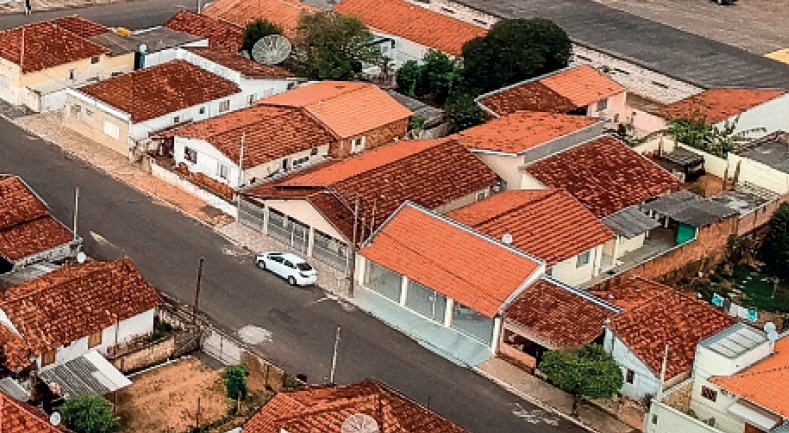 IMAGEM: fotografia aérea de um quarteirão com diversas casas. é a mesma casa da imagem anterior, porém, mais distante. FIM DA IMAGEM.