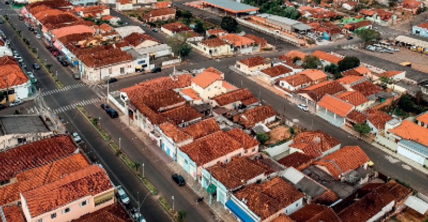 IMAGEM: fotografia aérea apresenta alguns quarteirões em um bairro residencial. nota-se uma avenida à esquerda da imagem. ainda há a mesma casa da imagem anterior, porém, mais distante. FIM DA IMAGEM.
