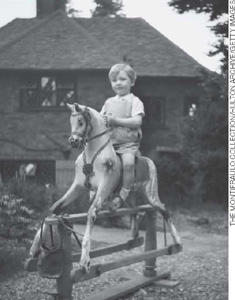 IMAGEM: foto antiga de um garoto sentado em um cavalo de brinquedo, preso a uma estrutura alta de madeira. FIM DA IMAGEM.