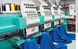 IMAGEM: produção de tecidos em uma fábrica, com máquina industriais. FIM DA IMAGEM.